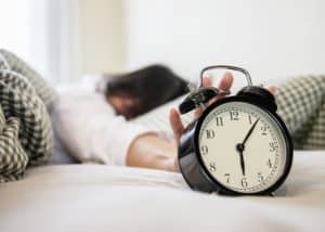 woman overslept reaching for the alarm